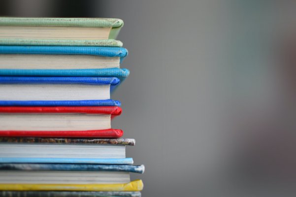 a stack of schoolbooks on a desk 